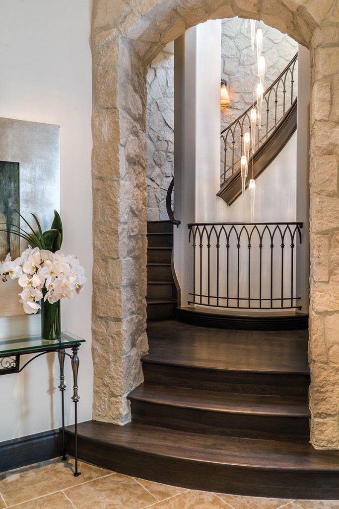 A fascinating light fixture illuminates a staircase of Texas limestone